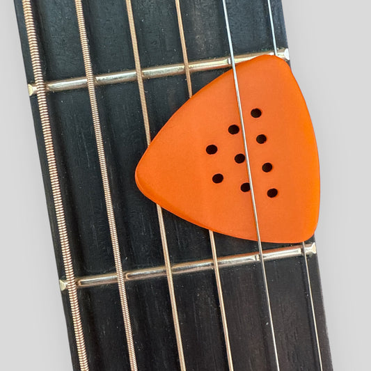 Orange guitar pick on a guitar fretboard